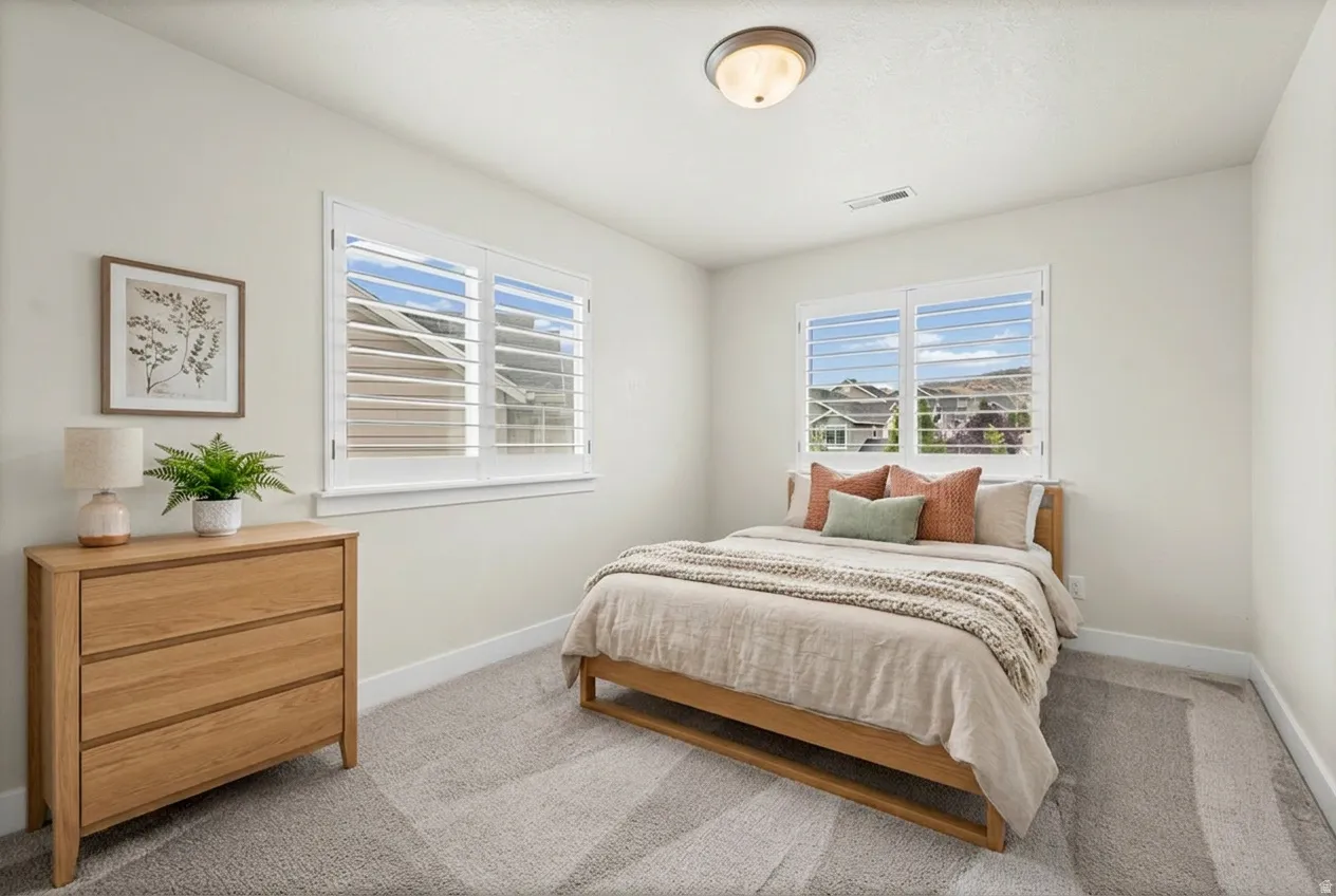 Bright interior space featuring two windows with white plantation shutters. Virtually staged.