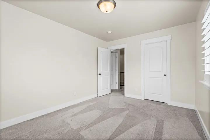 Neutral tone walls with white trim and grey patterned carpeting
