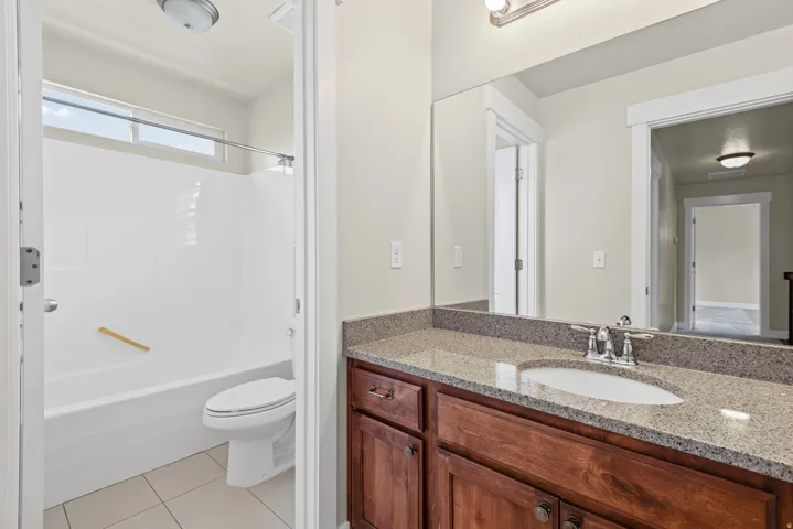 Bathroom featuring a wood vanity with a stone countertop, an undermount sink, and a large mirror