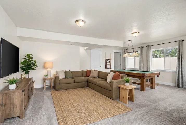 Spacious entertainment room featuring recessed lighting, a built-in media console, wood-finish flooring, and multiple windows with ample natural light. Virtually staged.