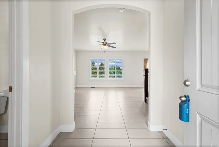 Entryway featuring a wide archway opening into a room with light tile flooring, high ceilings, and a ceiling fan