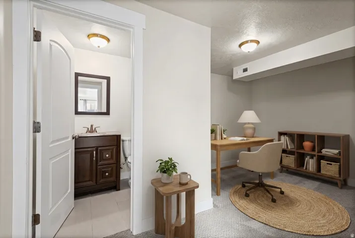 Well-lit private room with neutral gray walls and textured carpeting. Virtually staged.