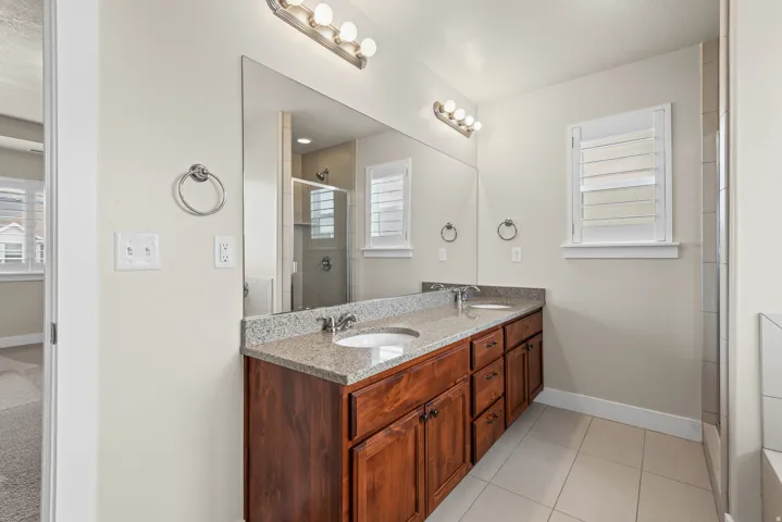 Spacious bathroom featuring a double vanity with wood-finish cabinetry, granite-style countertop, and dual undermount sinks