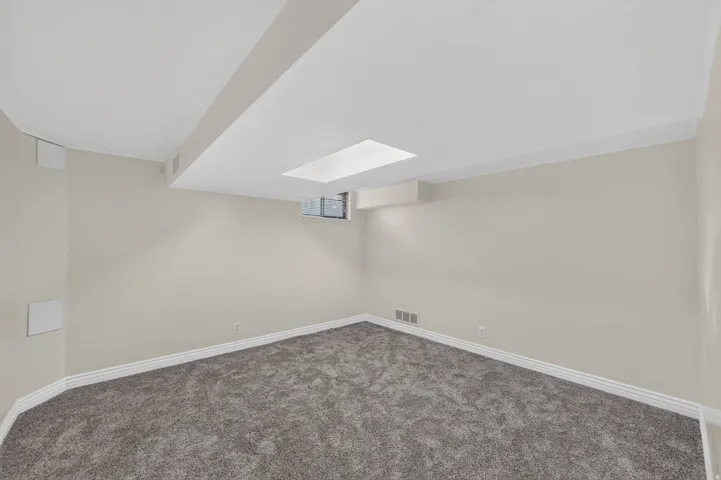 Carpeted room featuring light gray walls, white baseboards, and a recessed ceiling light fixture