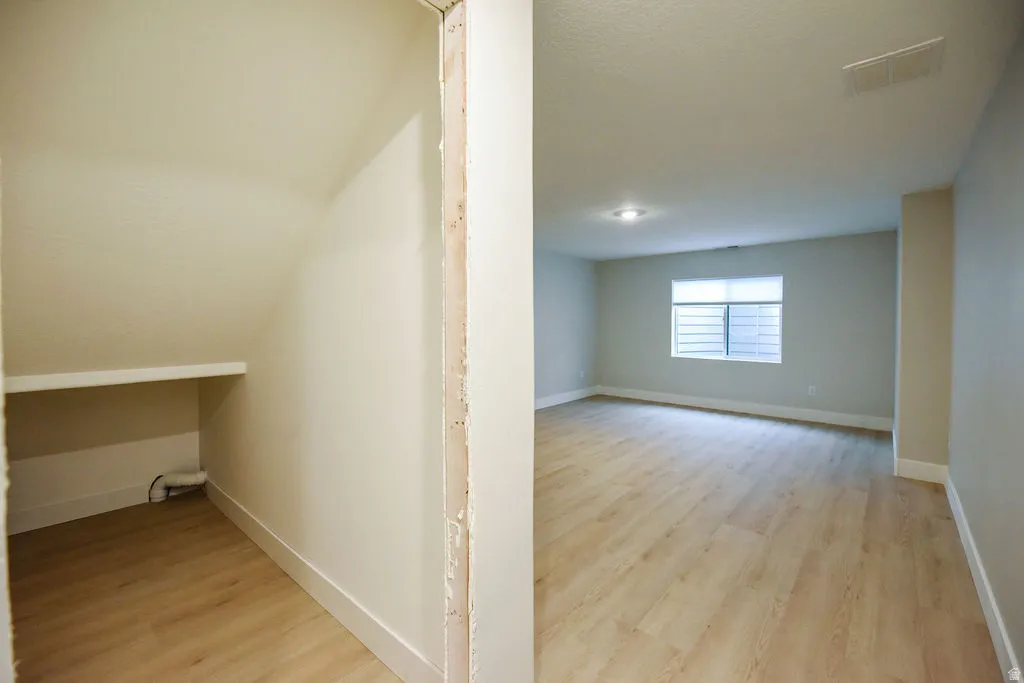 Spacious room with wood-finish flooring, recessed lighting, and a large egress window