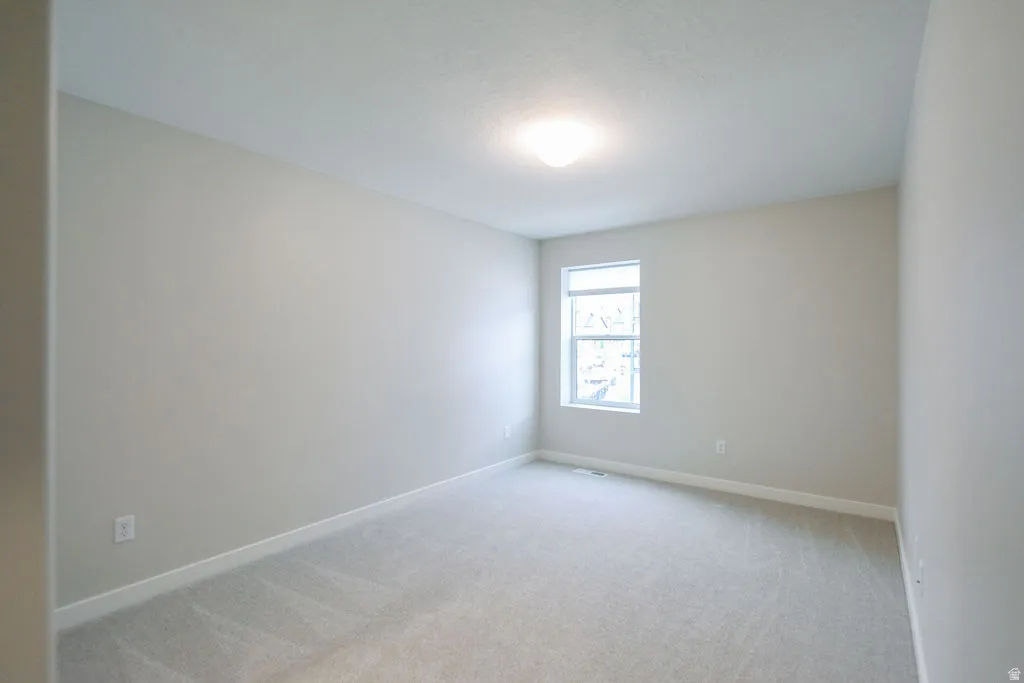 Room featuring light gray carpet, neutral wall paint, and a white trim baseboard