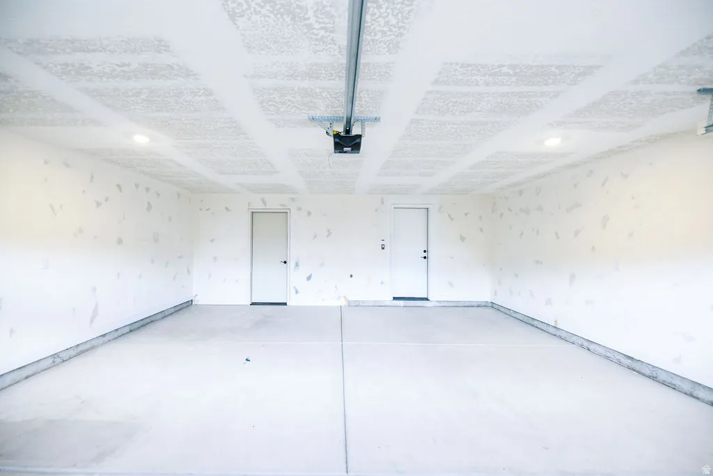 Spacious garage with concrete flooring, two access doors, and recessed lighting