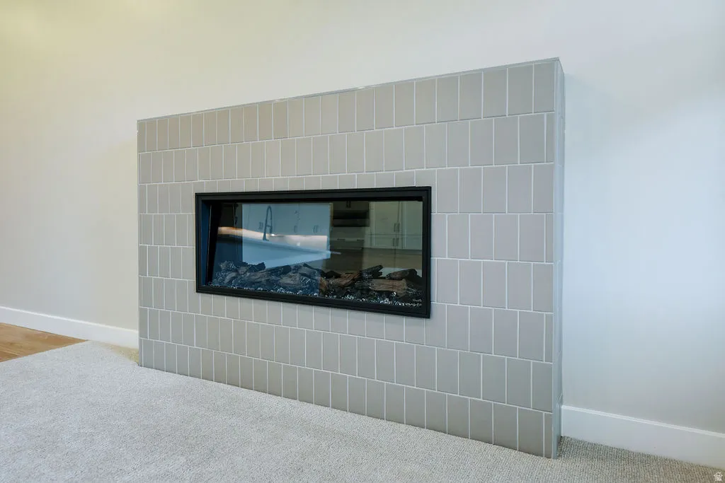 Modern fireplace featuring a horizontal glass enclosure and light gray subway tile surround