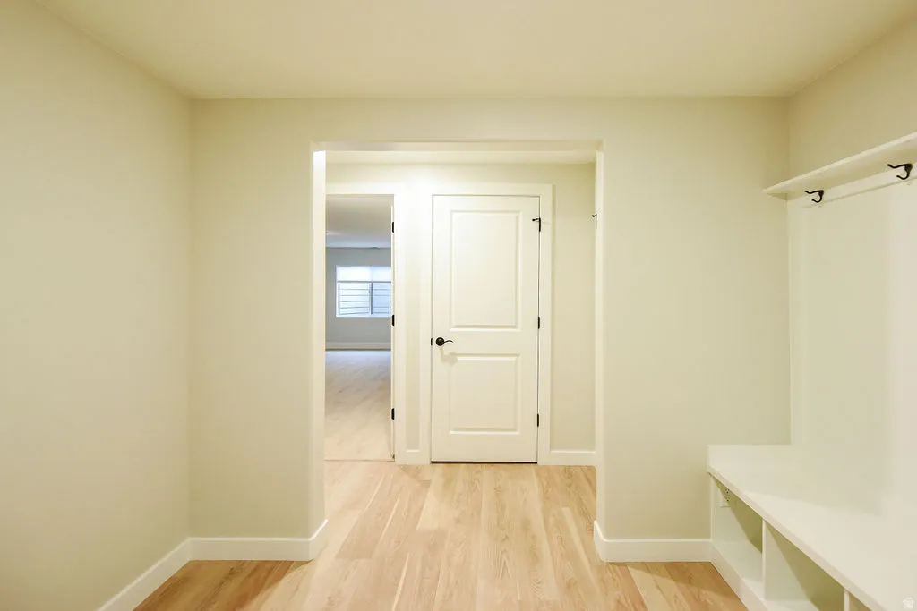 Entryway featuring light wood-finish flooring and a built-in white storage bench with cubbies