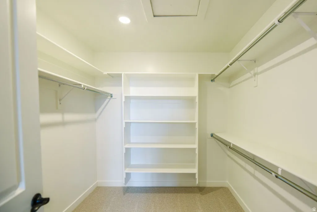 Walk-in closet featuring carpet flooring, built-in shelving, hanging rods, and recessed lighting