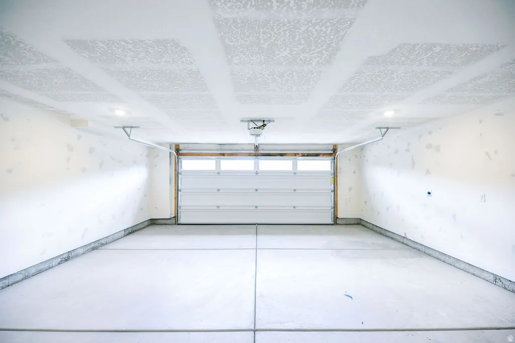 Spacious garage featuring a roll-up door with upper window panels, concrete flooring, and overhead lighting
