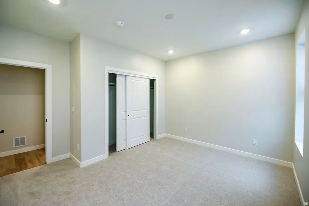 Carpeted room featuring recessed lighting, a window, and a sliding closet door