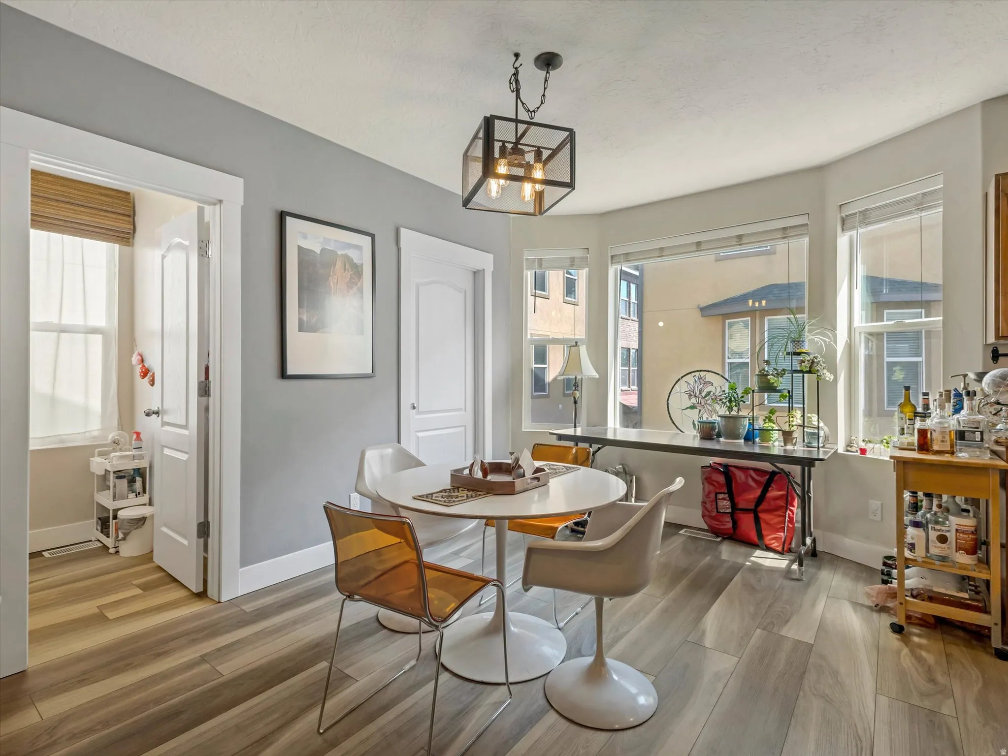 Dining area featuring wood-finish flooring, a contemporary ceiling light fixture, and multiple windows providing ample natural light