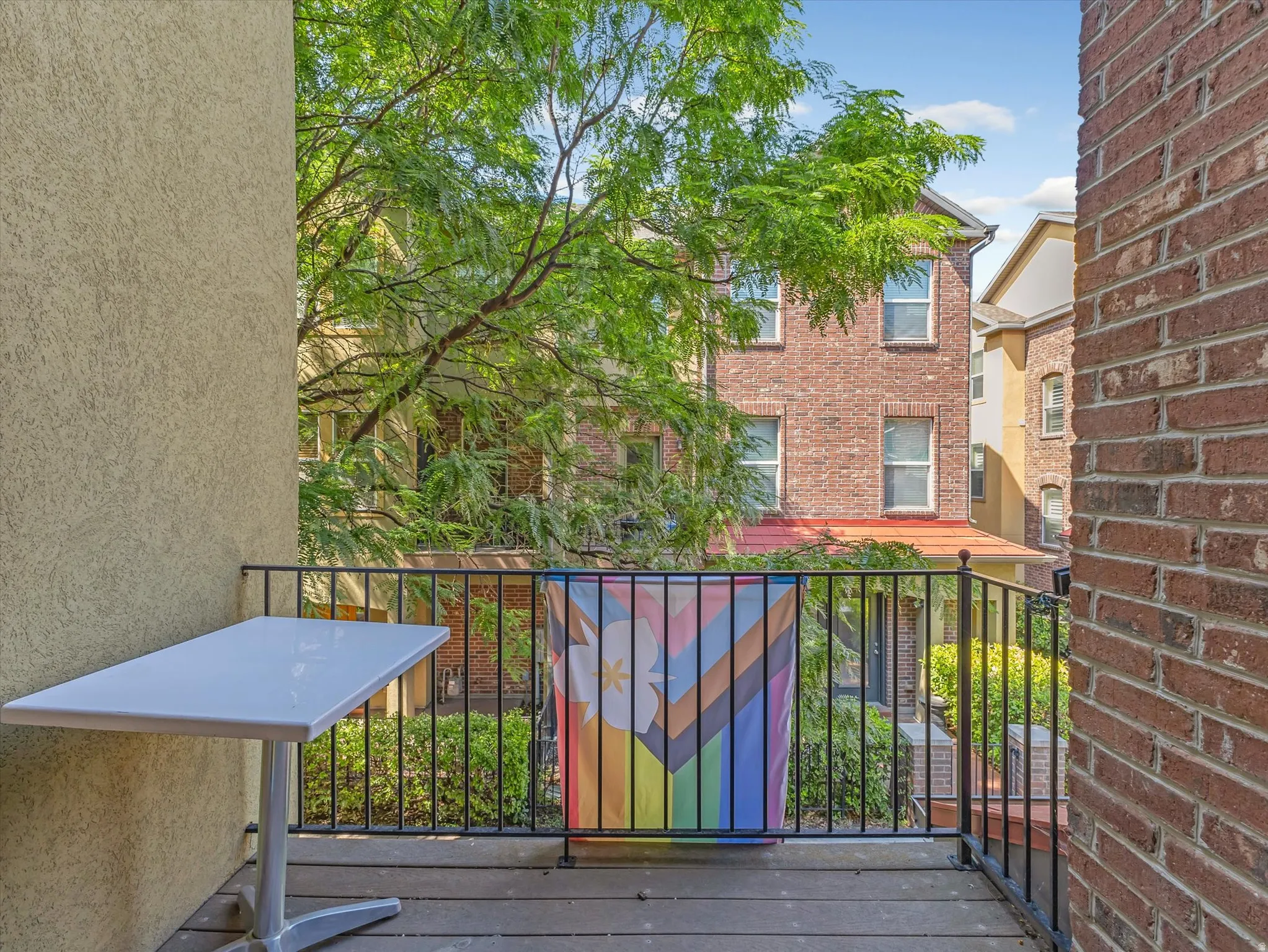 Private balcony featuring a stucco exterior wall, wrought iron railing, and wood-finish flooring