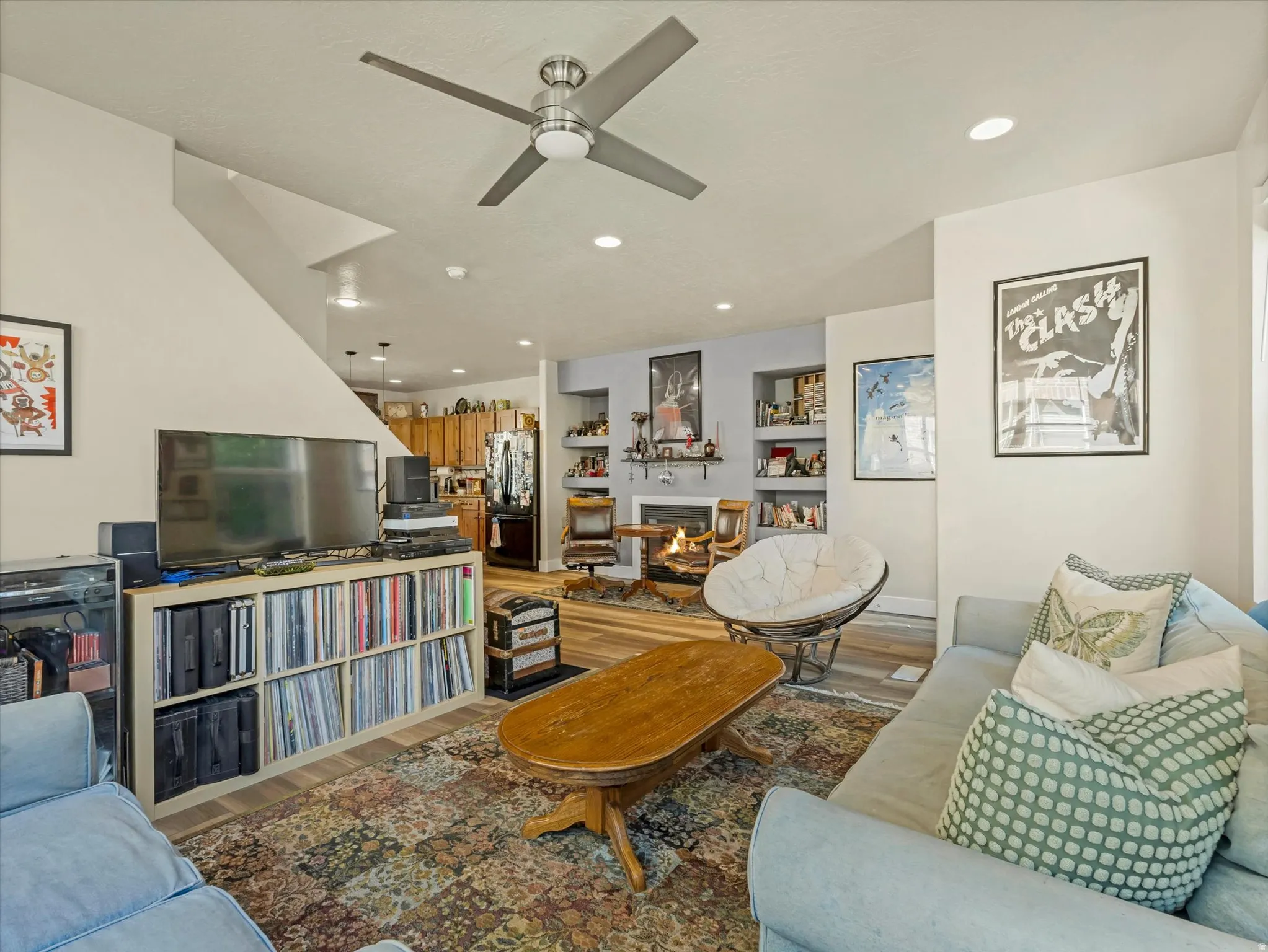 Living area featuring wood-finish flooring, a contemporary ceiling fan, recessed lighting, and a fireplace with built-in shelving
