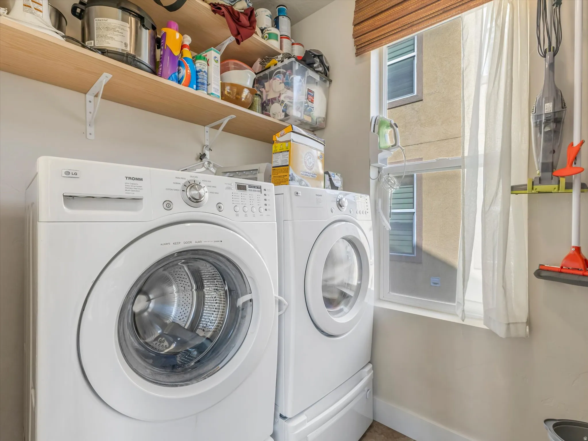 Dedicated laundry space featuring a window, built-in shelving, and a white washer and dryer set