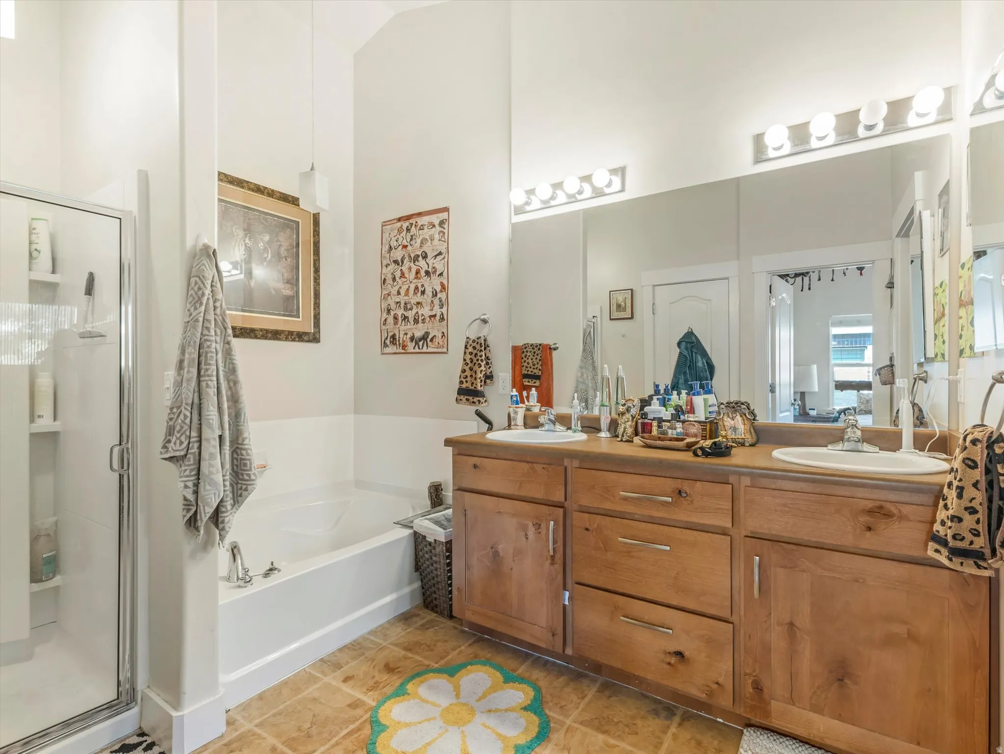 Bathroom featuring a double vanity with wood cabinetry, a large mirrored wall, and a combination shower/tub