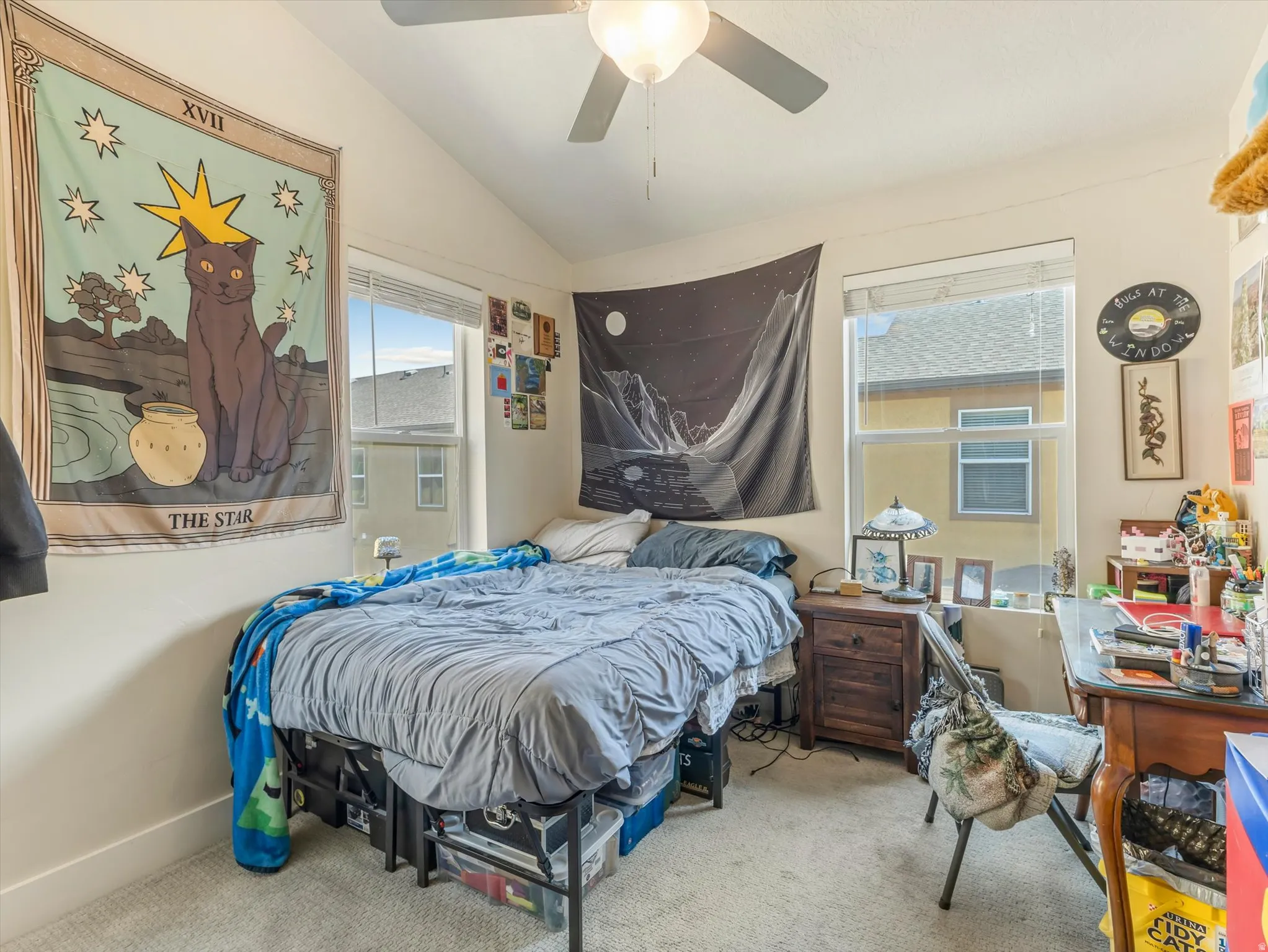 Room with vaulted ceiling, two windows featuring blinds, and a ceiling fan