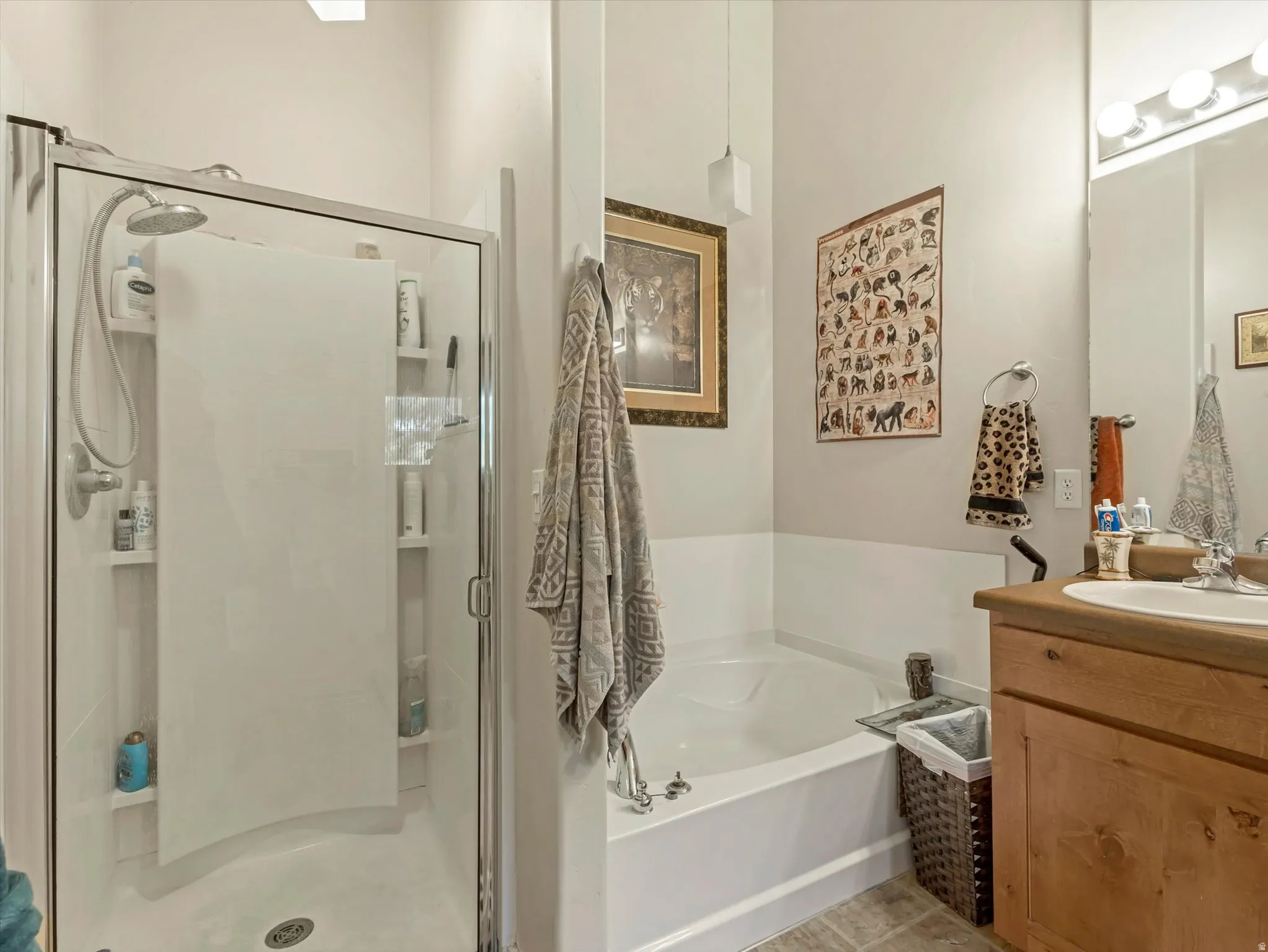 Full bathroom featuring a walk-in shower with built-in shelving, a separate soaking tub, and a wood-finish vanity with a white basin sink