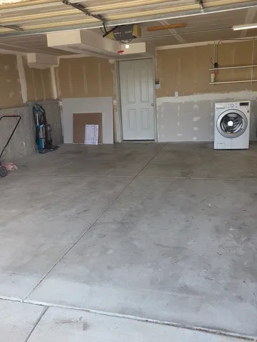 Concrete flooring garage with an integrated pedestrian door and overhead garage door track system