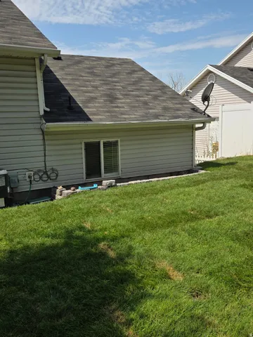 Exterior siding with a window, roofline, and lawn