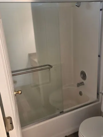 Bathroom featuring a bathtub and shower combination with sliding glass doors, a chrome showerhead, and a matching faucet