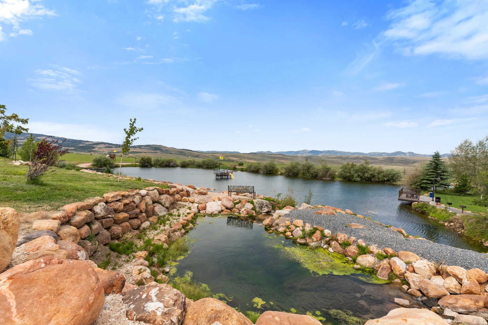 Expansive pond with a stone-lined perimeter, multiple docks, and surrounding green spaces
