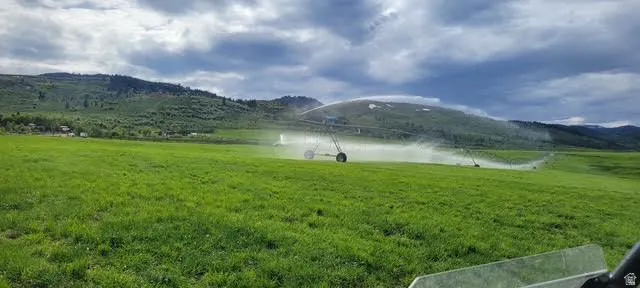 Expansive green field featuring an irrigation system with a mountain backdrop
