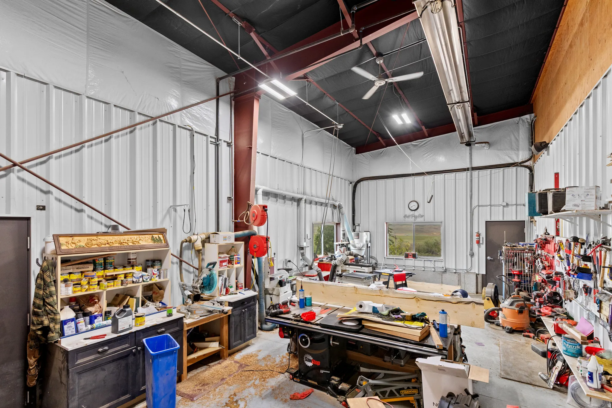 Spacious workshop featuring corrugated metal walls, exposed structural beams, and a high ceiling with overhead lighting