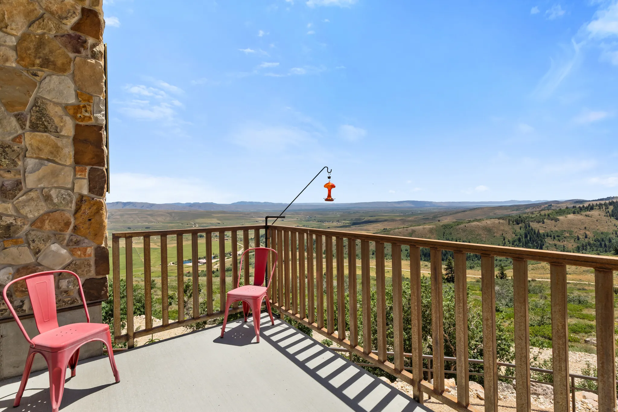 Outdoor balcony featuring a stone-clad wall, wooden railing, and expansive mountain scenery
