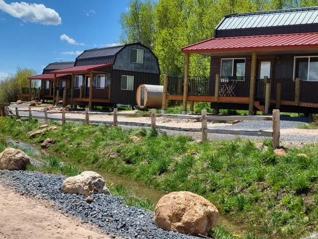 Multiple structures with dark siding, red metal roofs, and elevated wooden porches