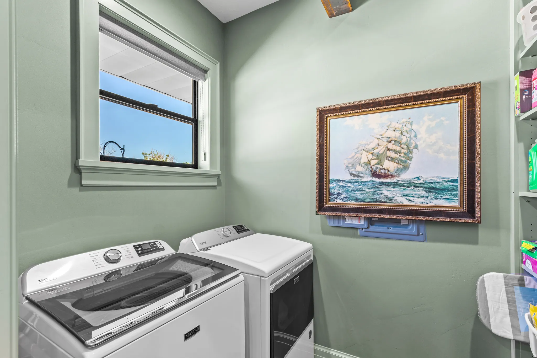 Laundry area with a single-pane window, light green painted walls, and built-in shelving
