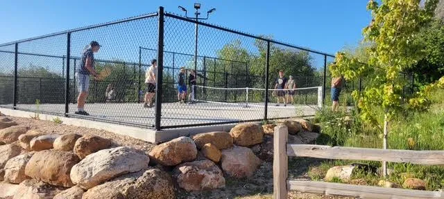 Recreational court with chain-link fencing, concrete base, and integrated lighting