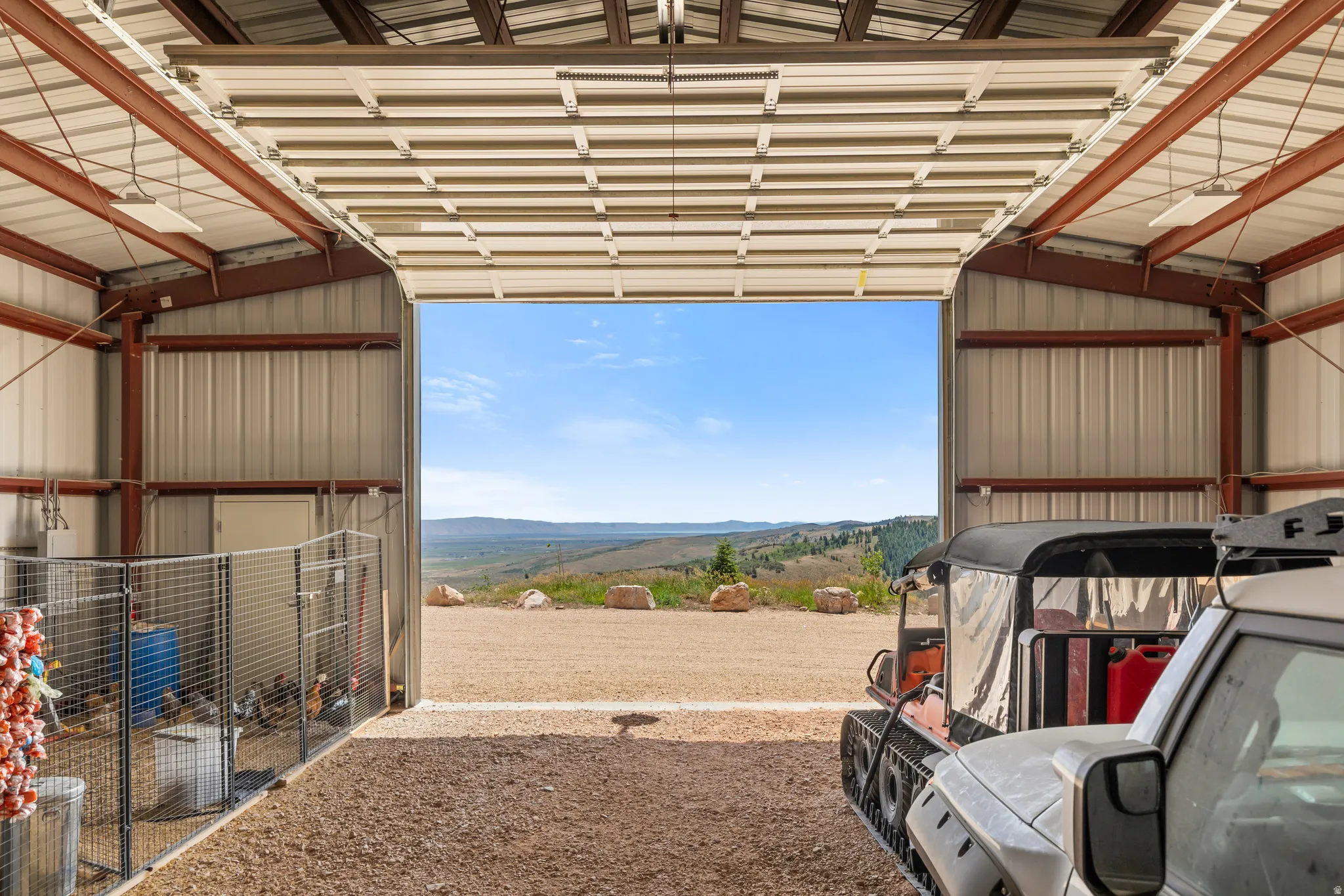 Spacious metal-sided outbuilding with exposed steel beam construction, a large roll-up door, and gravel flooring
