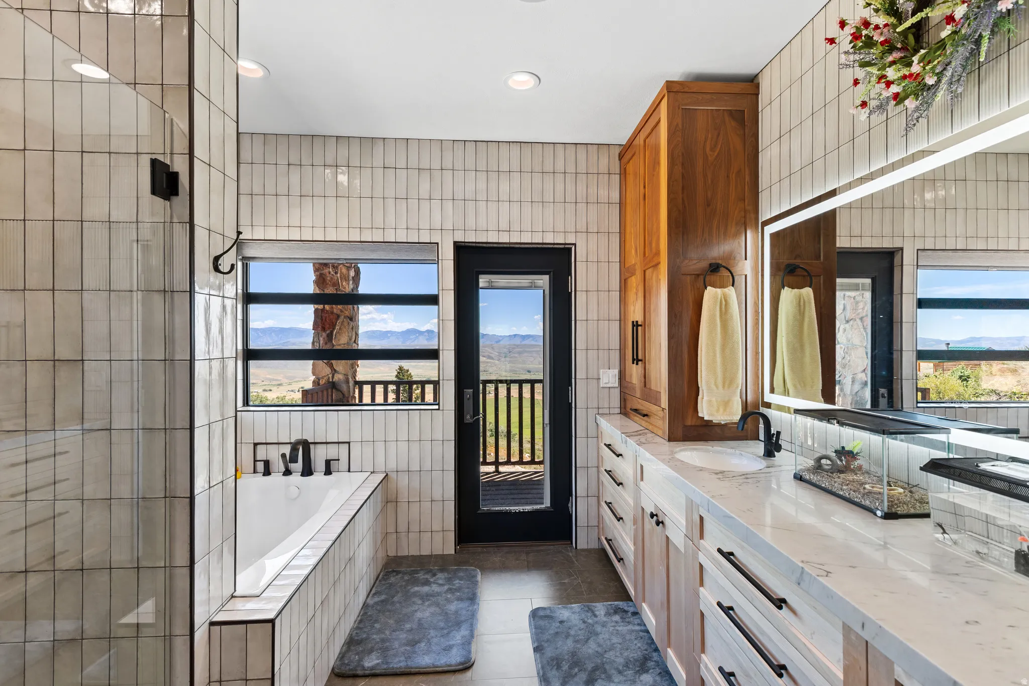 Bathroom featuring a soaking tub, glass-enclosed shower, dual vanity with undermount sinks, and a built-in wood cabinet