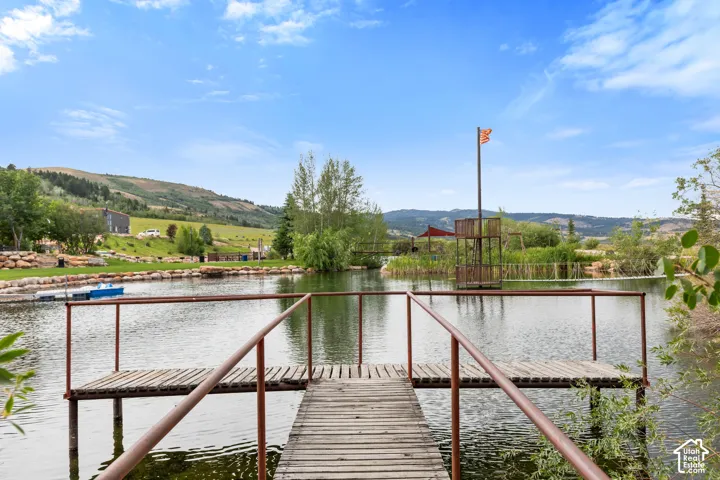 Wood dock extending over a pond, featuring a rustic metal railing and a wooden platform