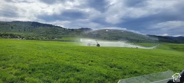 Expansive green field featuring an irrigation system with a mountain backdrop