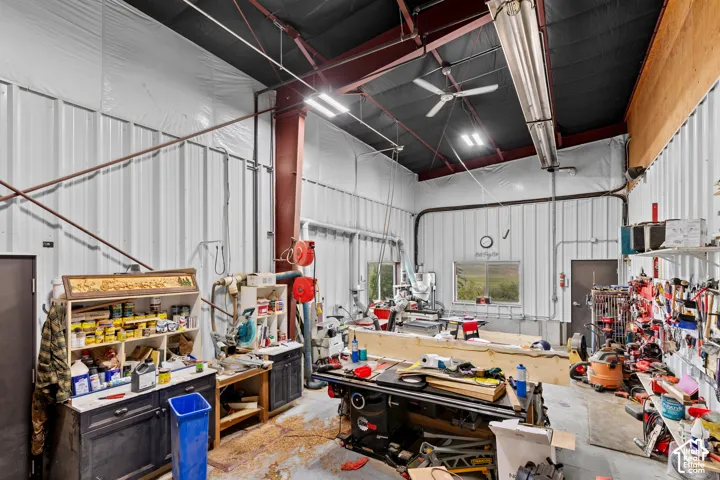 Spacious workshop featuring corrugated metal walls, exposed structural beams, and a high ceiling with overhead lighting