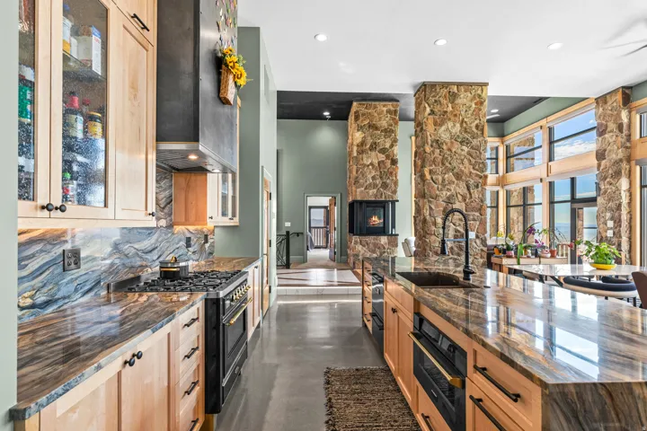Gourmet kitchen with custom cabinetry, integrated range, stone countertops, and a large central island featuring an under-mount sink