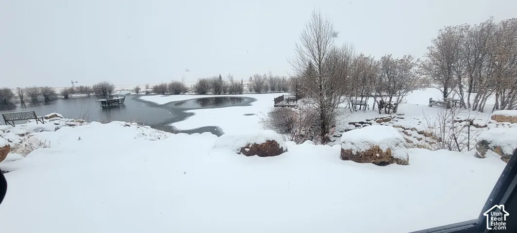 Pond with partially frozen surface, surrounded by snow-covered ground