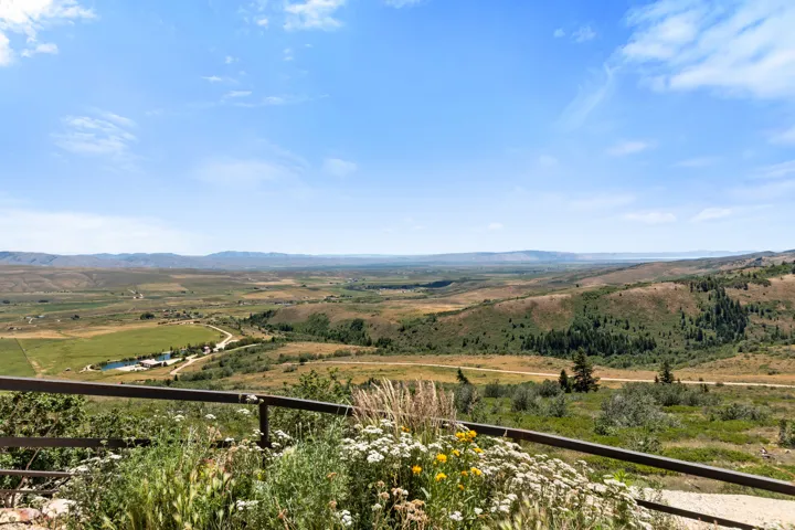 Expansive rural landscape featuring distant mountains and rolling hills with scattered trees