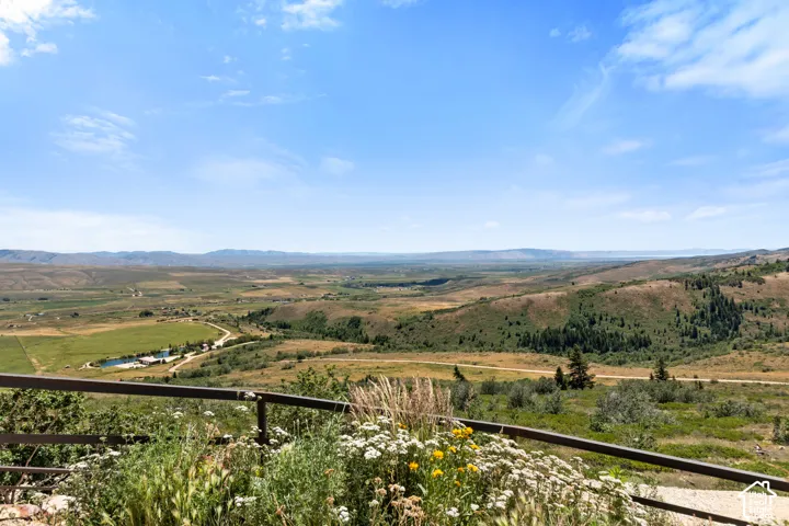 Expansive rural landscape featuring distant mountains and rolling hills with scattered trees