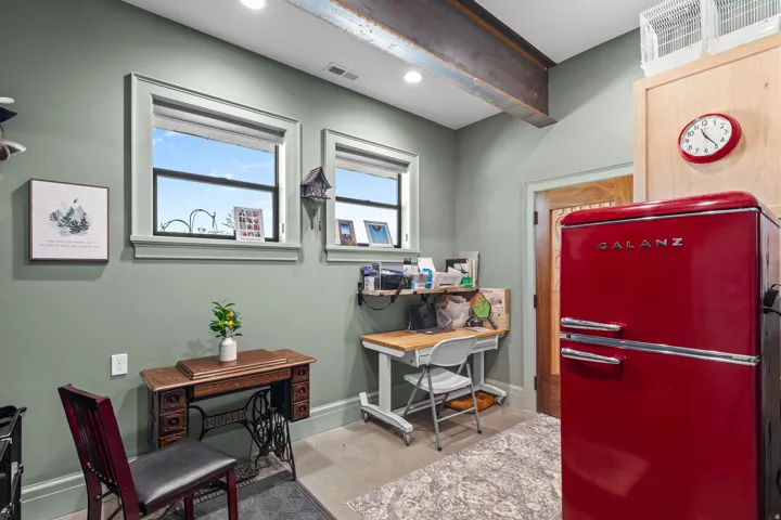 Exposed steel beam ceiling accenting a room with two windows, light green walls, and concrete flooring