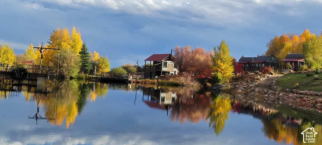 Waterfront property with multiple structures, mature trees with autumn foliage, and a serene water feature