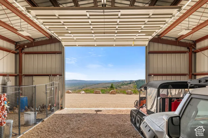 Spacious metal-sided outbuilding with exposed steel beam construction, a large roll-up door, and gravel flooring