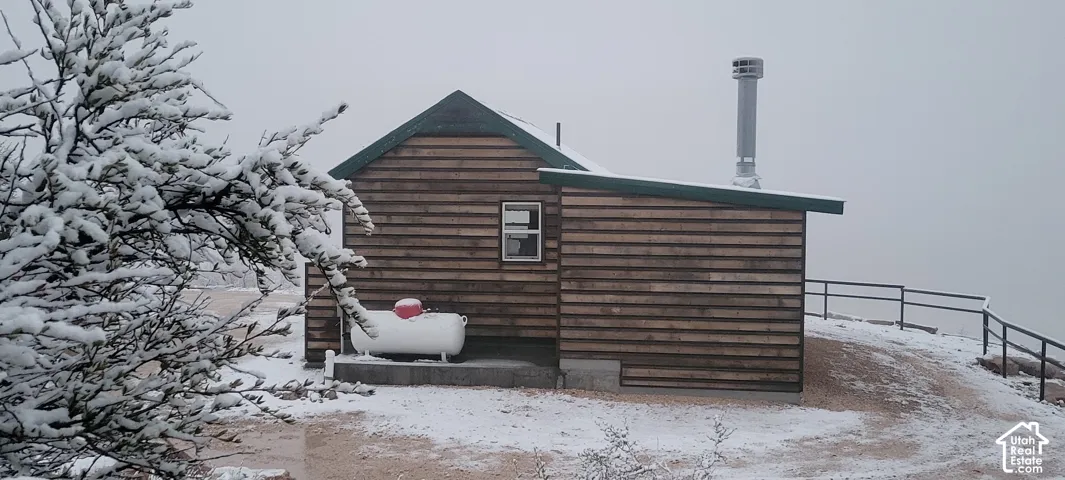 Wooden-sided structure featuring a metal chimney