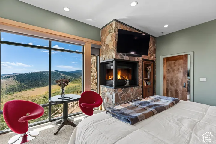 Floor-to-ceiling windows with expansive scenery, a stone-clad fireplace, built-in shelving, recessed lighting, and a solid wood door