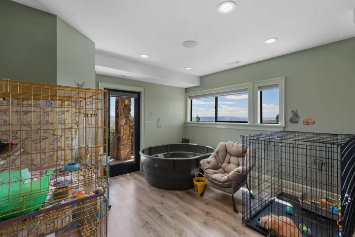Spacious room featuring light green walls, recessed lighting, and wood-finish flooring