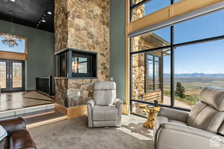 Soaring stone fireplace with a built-in firebox, floor-to-ceiling windows, and a panoramic mountain landscape