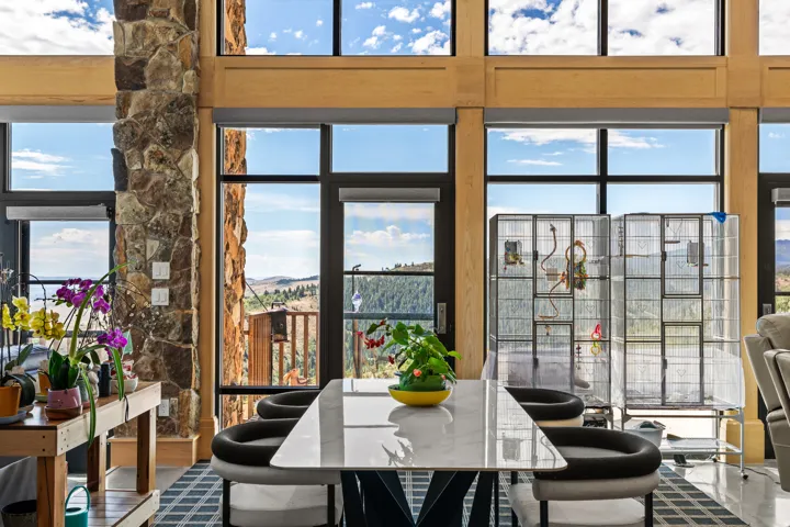 Expansive window wall with black framing, natural wood accents, and stone column detailing